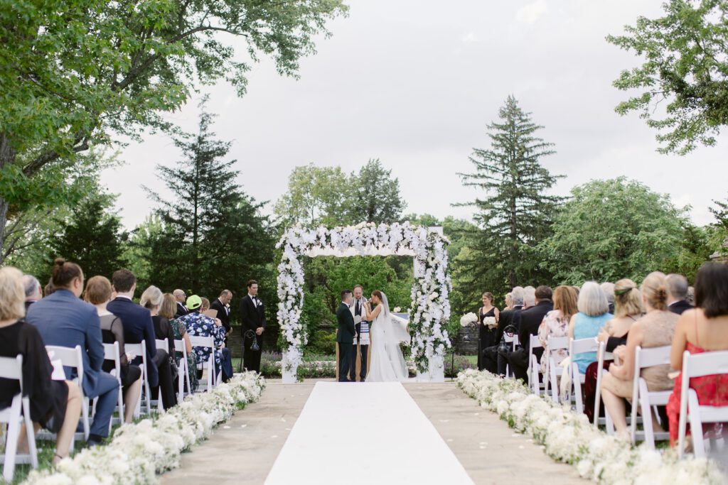 white chuppah, white aisle runner with flowers, green acres foundation