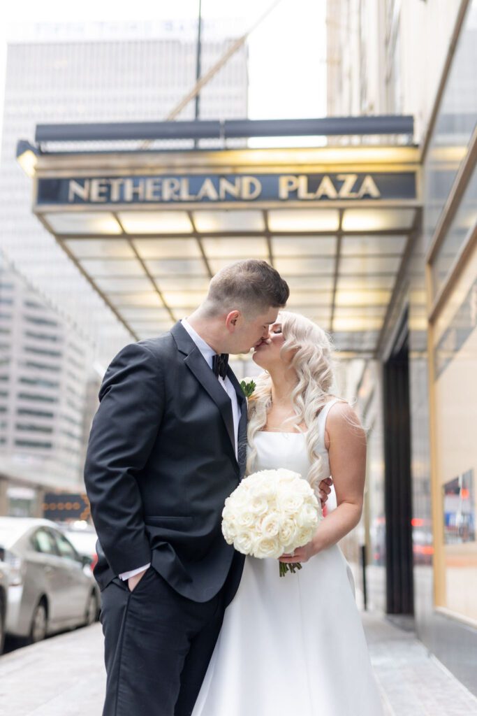 Bride and groom in front of the Hilton Cincy Netherland Plaza. White bridal bouquet flowers  