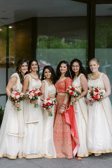 Bride with her bridesmaids. Seen are the bridesmaid bouquets with pink flowers, red flowers and greenery