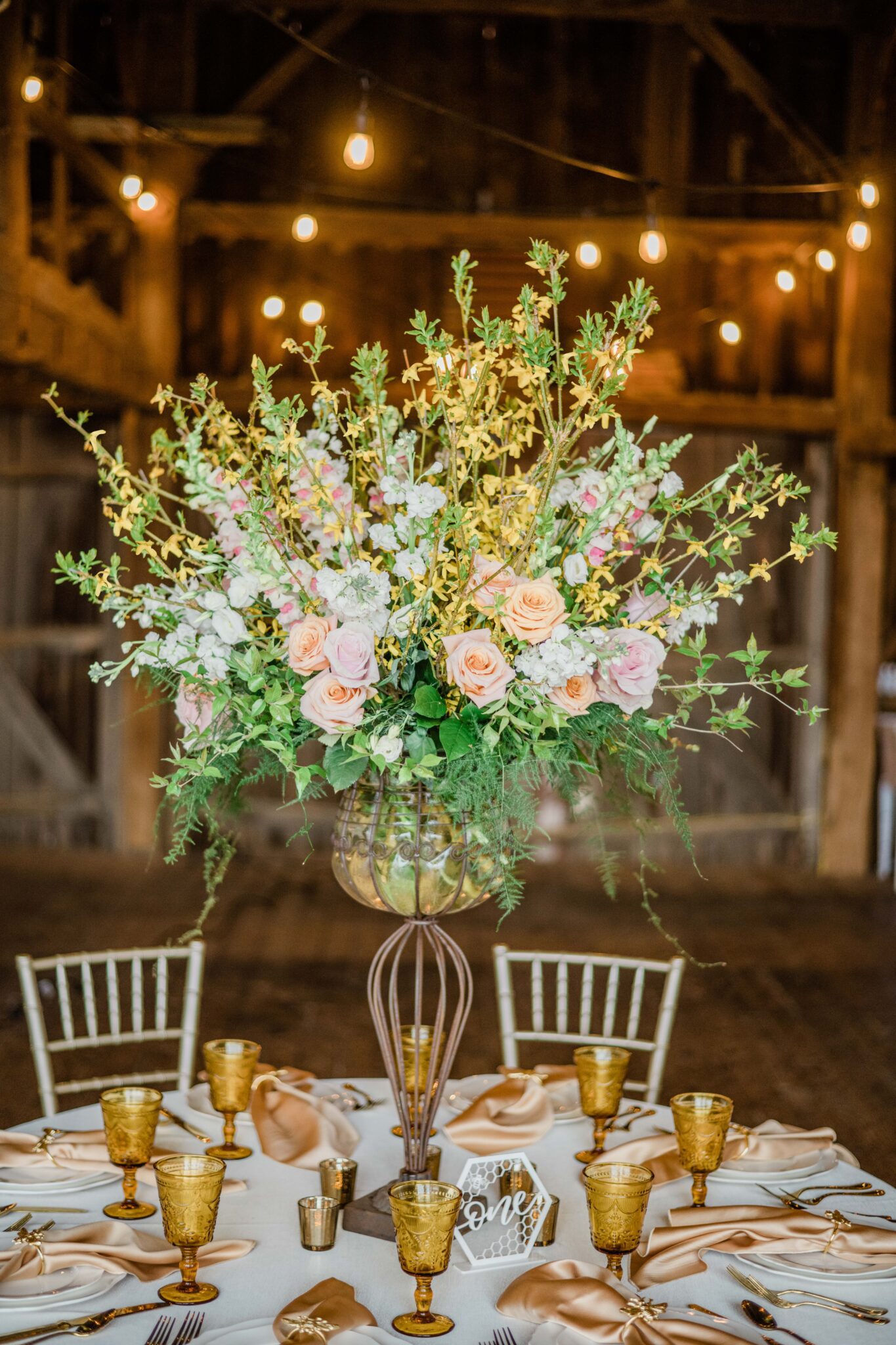Tall spring wedding table centerpiece of blooming branches and spring flowers in rustic barn at The honey farm by dayton wedding florist