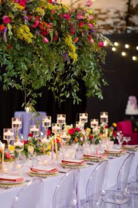 Colorful Wedding Floral Inspiration at the Brightside. This image has a wedding reception tablescape with a hanging floral installation above it. 